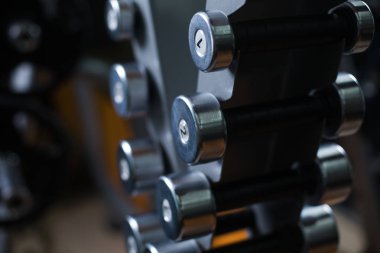 Küçük metal dumbbells bir bulanık spor salonu zemin üzerine sahibinin yakın çekim bir resim. Mesleki eğitim ve halter için donatım. Sağlıklı ve aktif egzersiz ağırlık kavramı ile.