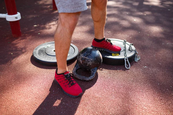 güçlü delikanlı ile seksi vücut egzersizleri kendi ayakları üzerinde yapıyor. adam parkta ayaklarıyla ağırlık kaldırıyor.