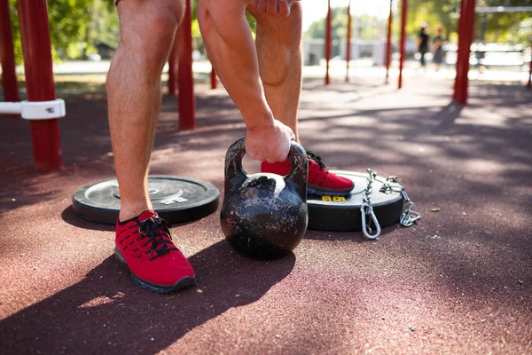güçlü delikanlı ile seksi vücut egzersizleri kendi ayakları üzerinde yapıyor. adam parkta ayaklarıyla ağırlık kaldırıyor.