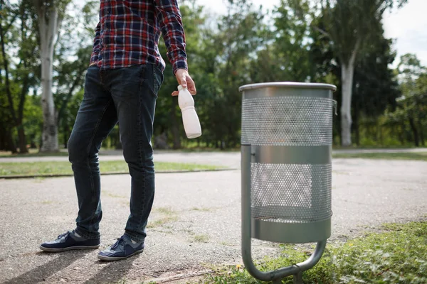 Erkek holding alt yeşil parkı güneşli günde çimenlerin üzerinde çöp yığını