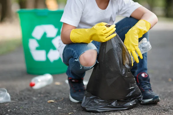 純度概念とアスファルト ボランティアの箱バッグにボトル プラスチックの空を拾って黄色の手袋での手 環境保護 — ストック写真