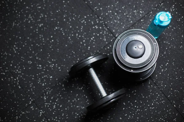 Üstten Görünüm mavi bir şişe su ve iki ağır metal halter için çiftler halinde güreşçiler, vücut geliştiriciler, spor oyuncular, rutinleri egzersiz programı içinde karanlık bir arka plan bulanık üzerinde spor salonları makineleri.