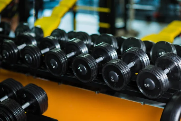 A full set of dumbbells, equipment for increasing strengh and muscle size, weight heavy sports routine, workouts, gyms on a dark blurred background.