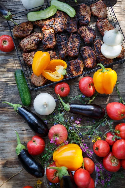 Ormanda ahşap bir masa üzerinde ızgara et ile taze sebze.