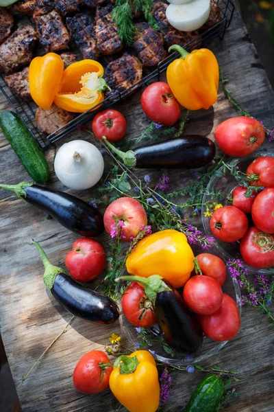 Ormanda ahşap bir masa üzerinde ızgara et ile taze sebze.