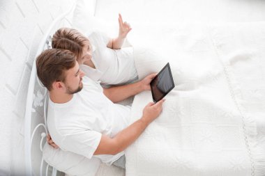 Güzel genç çift yatakta bir Tablet PC'yi kullanma.