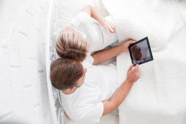 Güzel genç çift yatakta bir Tablet PC'yi kullanma.