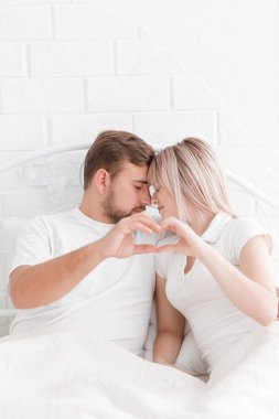 Çift el ile kalp şekli oluşturan yatakta yalan