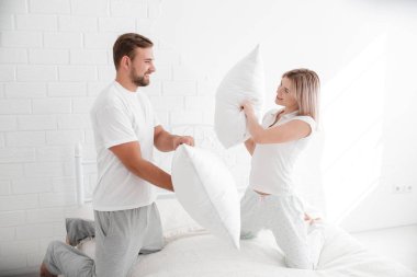 Genç bir çift yastık yatak odasında atıyor.