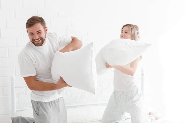 Молодая пара бьет подушки в спальне . — стоковое фото