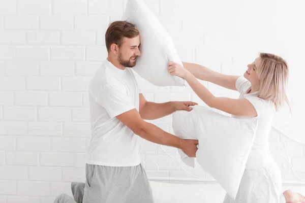 Una joven pareja está golpeando almohadas en el dormitorio . — Foto de Stock