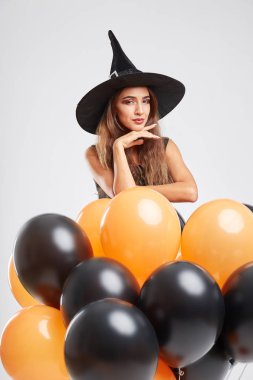 Gri bir arka plan üzerinde siyah ve turuncu balonlarla bir cadı kostümü seksi kız. Halloween cadı kavramı.