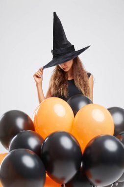 Gri bir arka plan üzerinde siyah ve turuncu balonlarla bir cadı kostümü seksi kız. Halloween cadı kavramı.