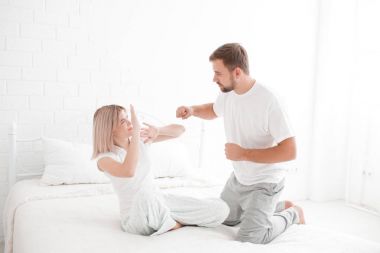 Bir adam bir kız yatakta beyaz zemin üzerine vurmak istiyor