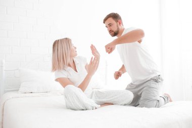 Bir adam bir kız yatakta beyaz zemin üzerine vurmak istiyor