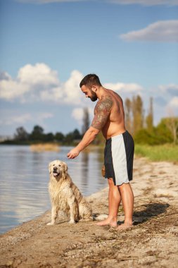 Mutlu labrador zevk sahibi ile sahilde oynarken.