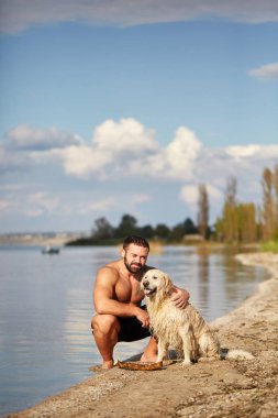 Mutlu labrador zevk sahibi ile sahilde oynarken.