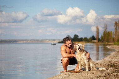 Mutlu labrador zevk sahibi ile sahilde oynarken.