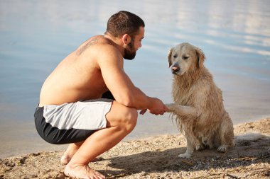 Mutlu labrador zevk sahibi ile sahilde oynarken.