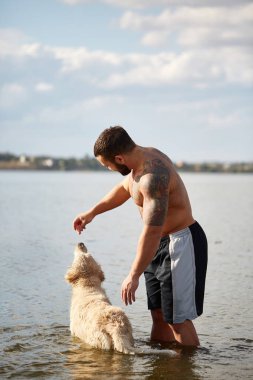 Mutlu labrador zevk sahibi ile sahilde oynarken.
