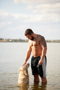 Mutlu labrador zevk sahibi ile sahilde oynarken.