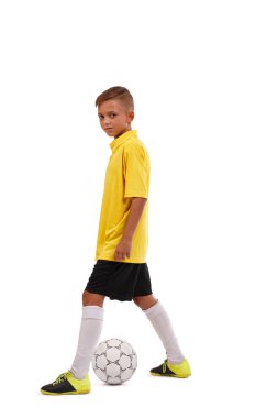 Beyaz bir arka plan üzerinde izole sportif sevimli okul çocuğu tekme futbol topu. Spor giyim kavramı.