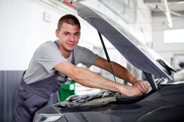 Olgun bir beyaz adam araba motoru başlık altında bir yağ seviye kontrol.