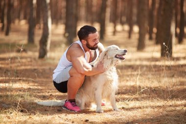 Ormanda açık yürüyen labrador köpek ile güçlü esmer adam.