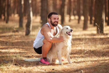 Ormanda açık yürüyen labrador köpek ile güçlü esmer adam.