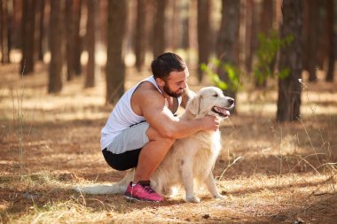 Ormanda açık yürüyen labrador köpek ile güçlü esmer adam.