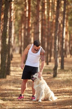 Ormanda açık yürüyen labrador köpek ile güçlü esmer adam.