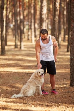 Ormanda açık yürüyen labrador köpek ile güçlü esmer adam.