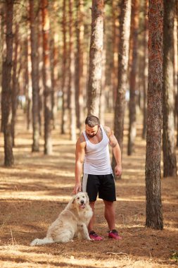 Ormanda açık yürüyen labrador köpek ile güçlü esmer adam.