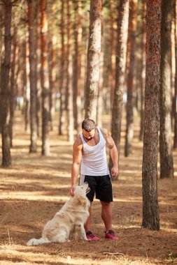 Ormanda açık yürüyen labrador köpek ile güçlü esmer adam.