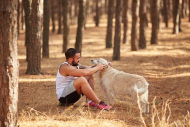 Ormanda açık yürüyen labrador köpek ile güçlü esmer adam.