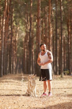 Ormanda açık yürüyen labrador köpek ile güçlü esmer adam.