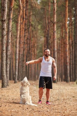 Ormanda açık yürüyen labrador köpek ile güçlü esmer adam.