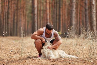 Bir adam bir köpek için a yürümek ormanda okşayarak