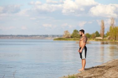 Dövmeler, yakışıklı, genç bir adam sahilde duruyor