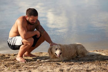 Bir adam köpeğini bir nehir arka planı okşayarak
