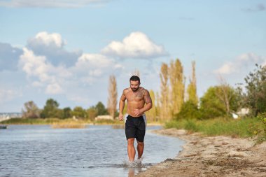 Genç bir adam Güney Bug Nehri plaj boyunca jogs