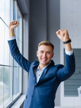 Office arka plan üzerinde tezahürat gülümseyen iş adamı. Mutlu ofis çalışanı. İş başarı kavramı.