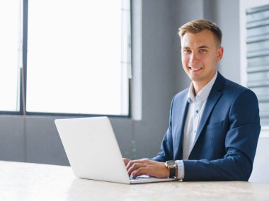 Yakışıklı iş adamı bir dizüstü bilgisayarda office arka plan üzerinde çalışıyor. Dijital teknoloji kavramı. Kopya alanı.