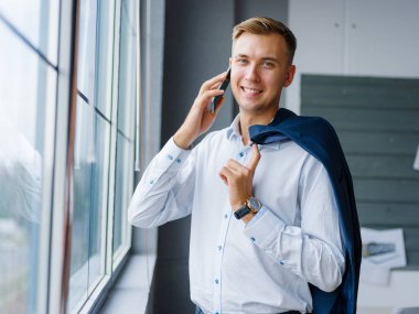 Gülümseyen office adam bir cep telefonu üzerinde arka plan bulanık arıyor. Ağ kavramı. Kopya alanı.