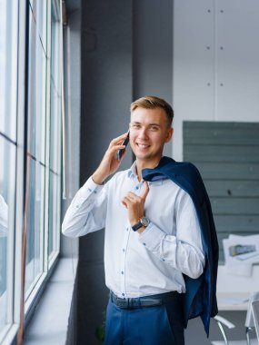 Gülümseyen office adam bir cep telefonu üzerinde arka plan bulanık arıyor. Ağ kavramı. Kopya alanı.