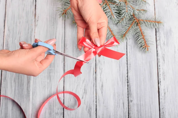 Hands with scissors to clip the red bow.