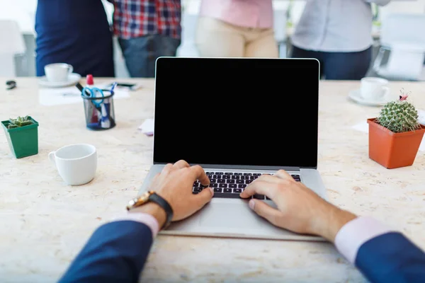 Laptop from the first person on the background of a group of office workers