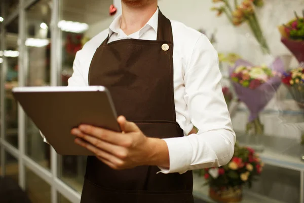 Close-up florist working on tablet on a blurred background. Progressive small business concept.