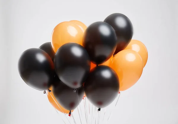 Floating orange and black balloons for a Halloween party on a light background. Halloween decorations. — Stock Photo, Image