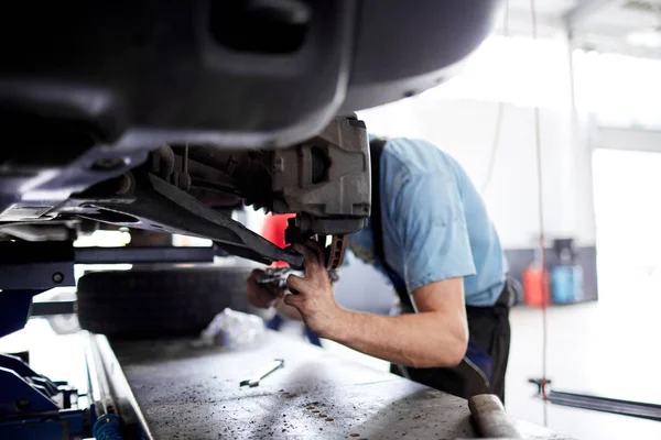 Der Mechaniker repariert die Bremsen an der kaputten Maschine — Stockfoto